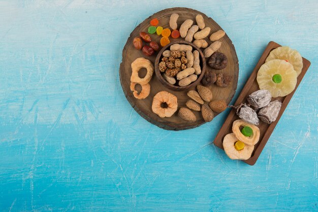 Foto gratuita frutta secca e snack in piatti di legno sul tavolo blu