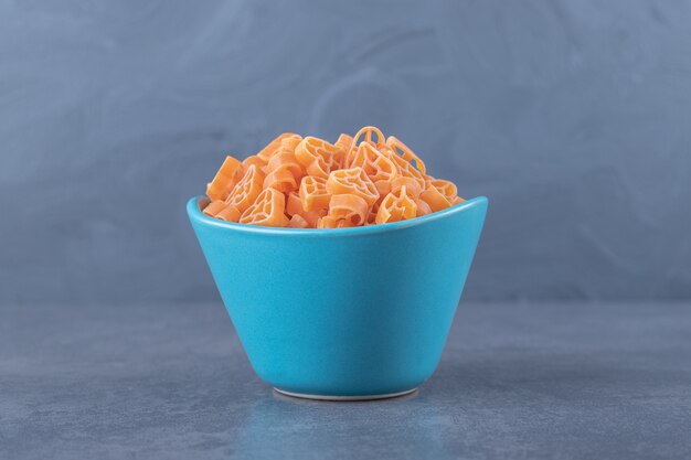 Dry heart-shaped pasta in blue bowl.