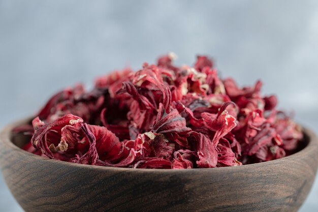 Dry hibiscus tea in wooden bowl.