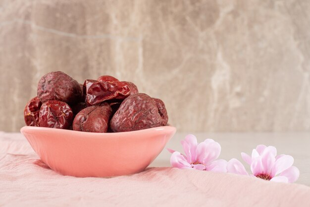 Dry jujube berries in a cup on concrete.