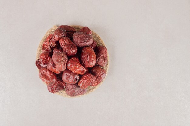 Dry jujube berries in a cup on concrete.