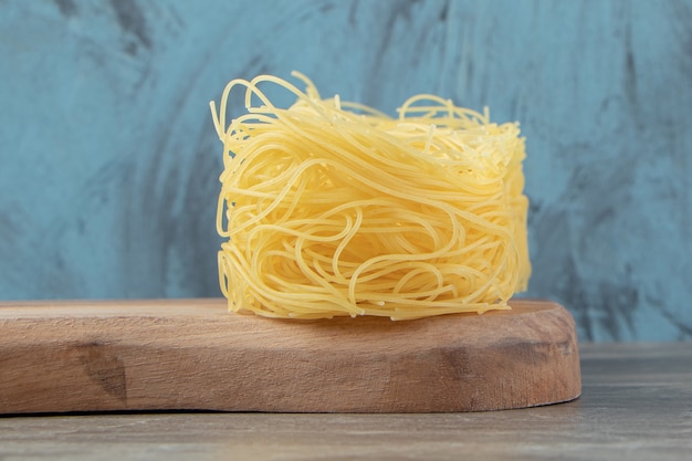 Dry noodle nests on wooden board.