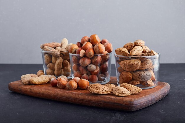 Dry nuts in glass cups on a wooden platter. 