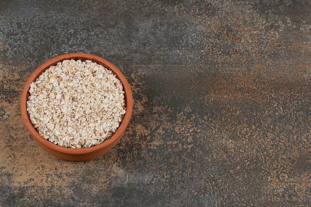 Dry oat flakes in ceramic bowl. 