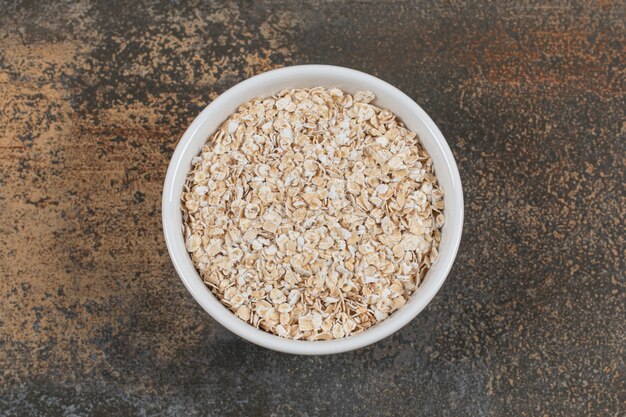 Dry oat flakes in white bowl. 