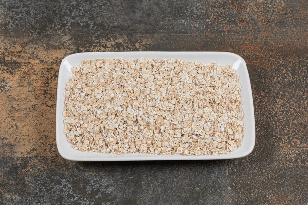 Dry oat flakes on white plate. 