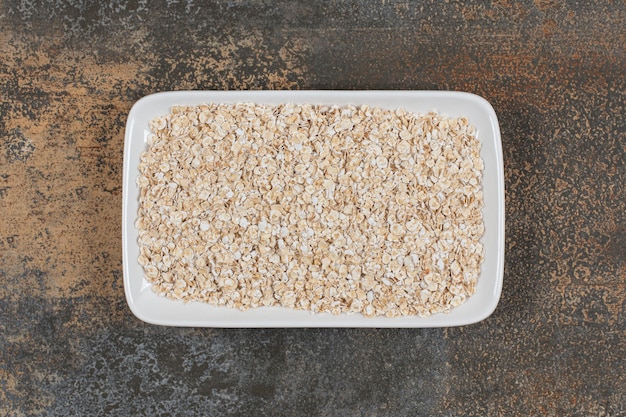 Dry oat flakes on white plate. 