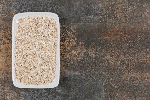 Dry oat flakes on white plate. 