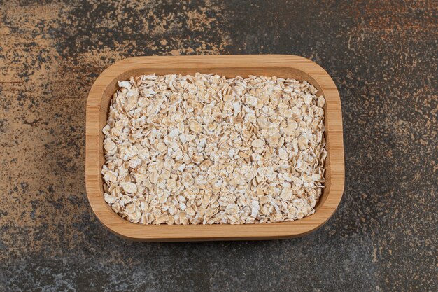 Dry oat flakes on wooden plate. 