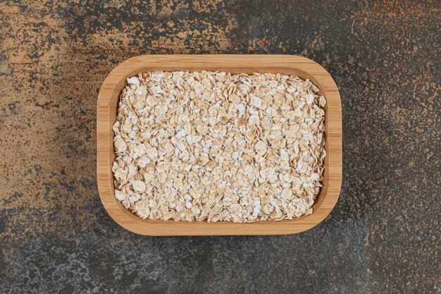 Dry oat flakes on wooden plate. 