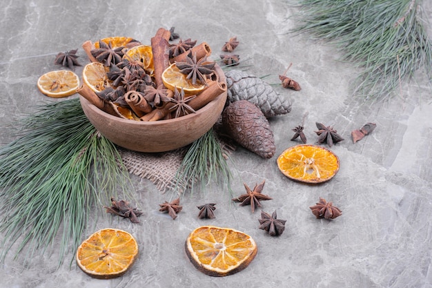 Dry orange slices, cinnamon sticks and anise flowers in a wooden cup