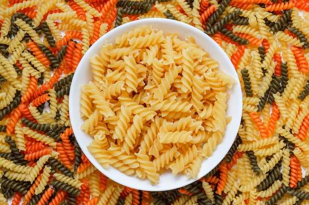 Free photo dry pasta in a white plate on macaroni table, flat lay.