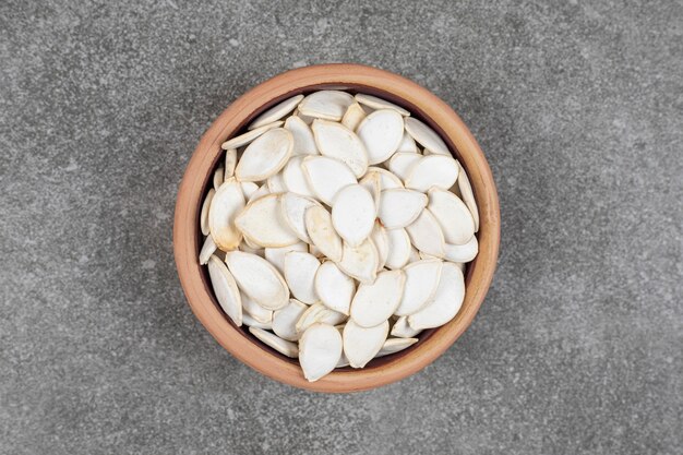 Dry pumpkin seeds in ceramic bowl.