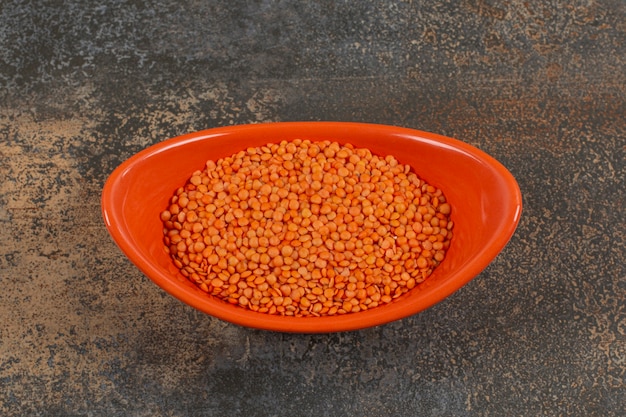 Free photo dry red lentils in orange bowl.
