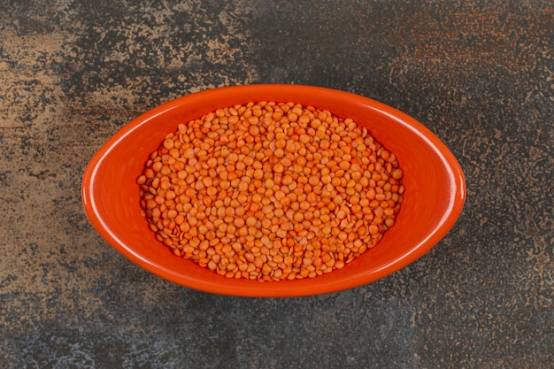 Free photo dry red lentils in orange bowl.