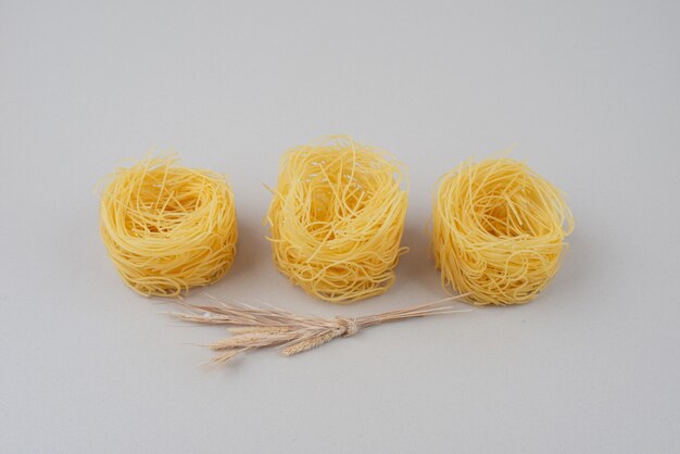 Dry spaghetti nests on white with wheat.