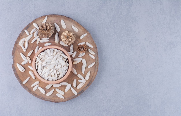 Dry sunflower seeds in bowl on a board on the marble surface