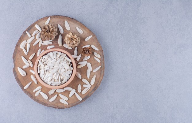 Dry sunflower seeds in bowl on a board on the marble surface