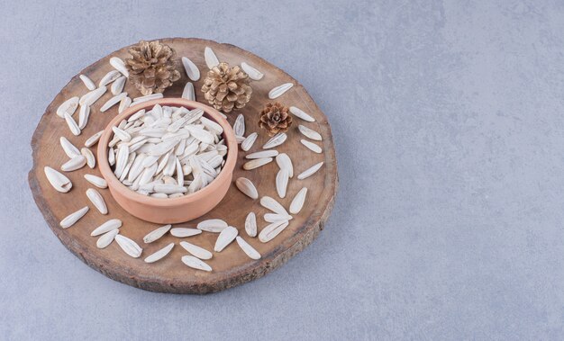 Dry sunflower seeds in bowl on board on marble.