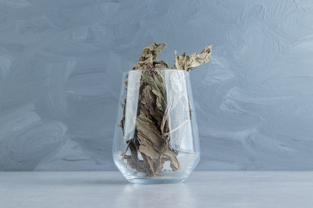 Dry tea leaves in glass on stone surface