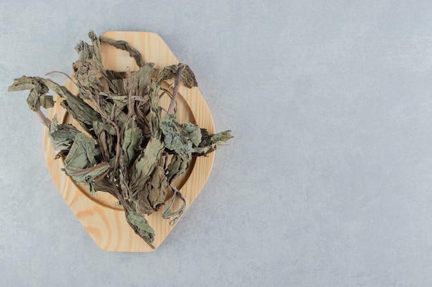 Dry tea leaves on wooden plate.  