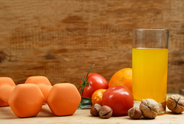 Dumbbell, orange juice, fruit and nuts on the wooden table, sport and health lifestyle concept