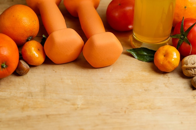 Dumbbell, orange juice, fruit and nuts on the wooden table, sport and health lifestyle concept