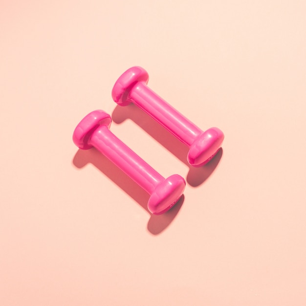 Dumbbells flat lay on pink background