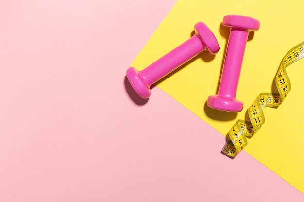 Free photo dumbbells flat lay on pink and yellow background