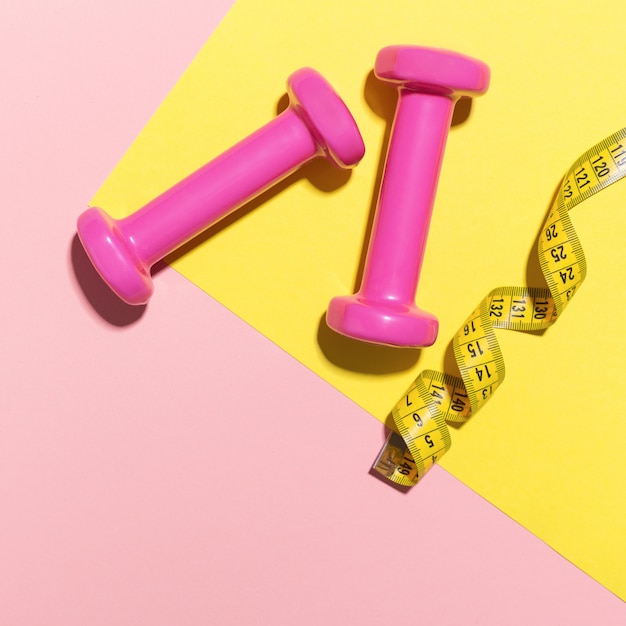 Dumbbells flat lay on pink and yellow background