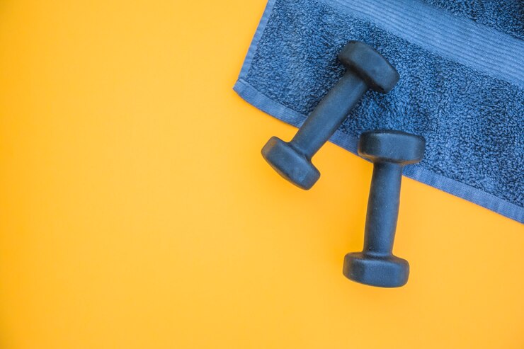 Free Photo dumbbells on towel over yellow background