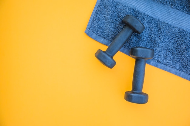 Dumbbells on towel over yellow background