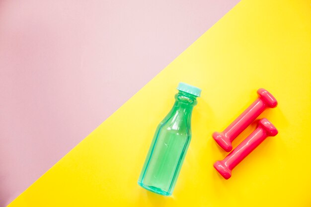 Dumbbells and water on colorful background