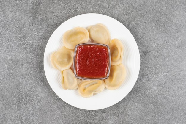 Free photo dumplings filled with meat and ketchup on white plate