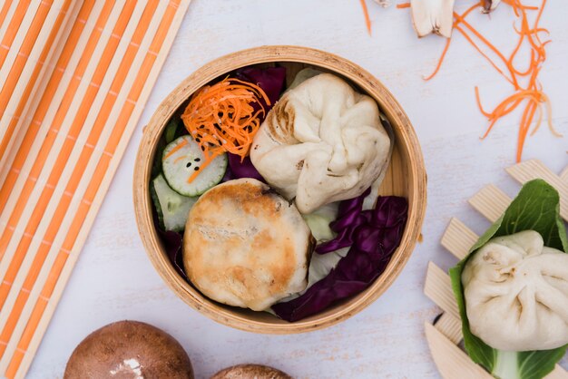 Dumplings and salad in steamer on backdrop