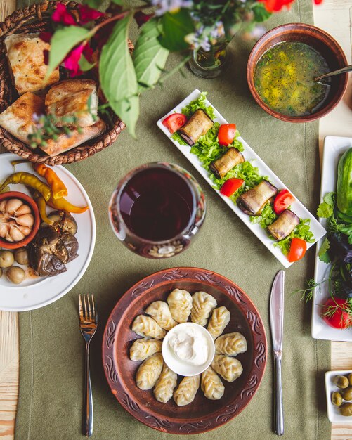 Dumplings served with sour cream eggplant rolls and pickles