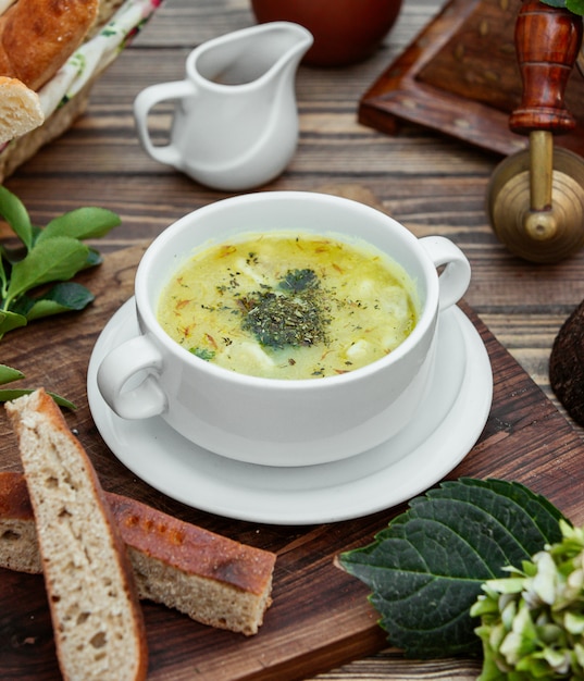 dushbara dumpling soup served with bread on wooden table