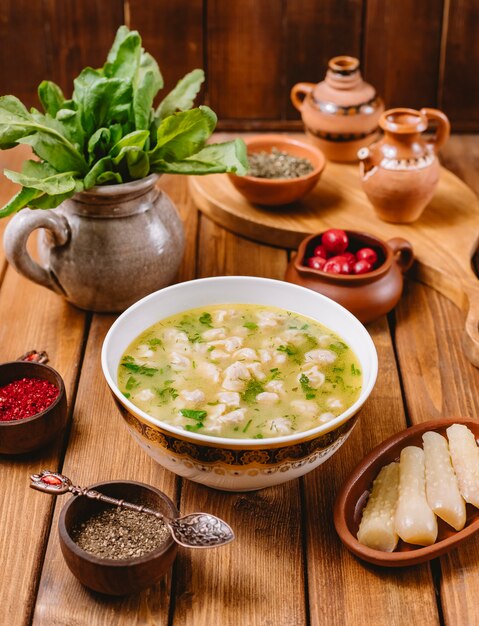 Dushbara dumpling soup served with dried herbs and spices vertical