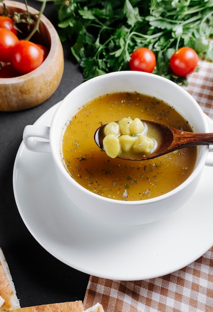 Dushbara traditional soup served with herbs and tomatoes on the table