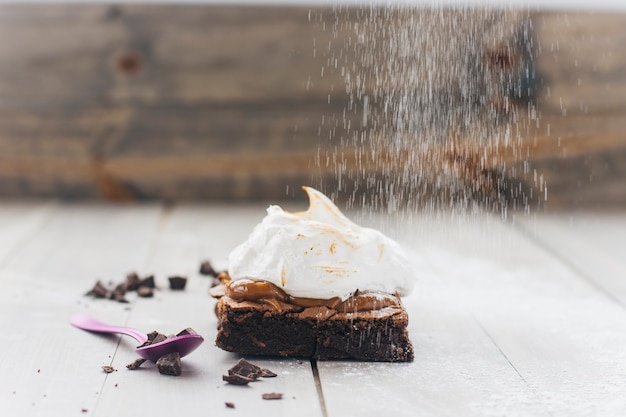 Dusting pastry with powder sugar on wooden surface