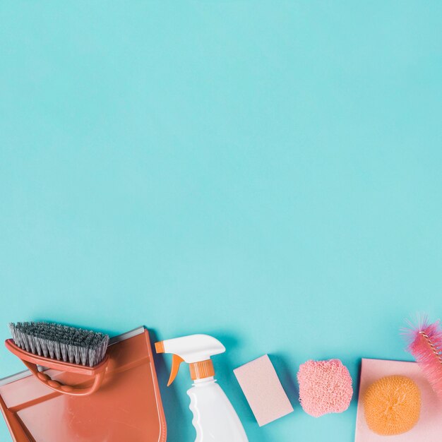 Dustpan, spray bottle and scrub on turquoise background