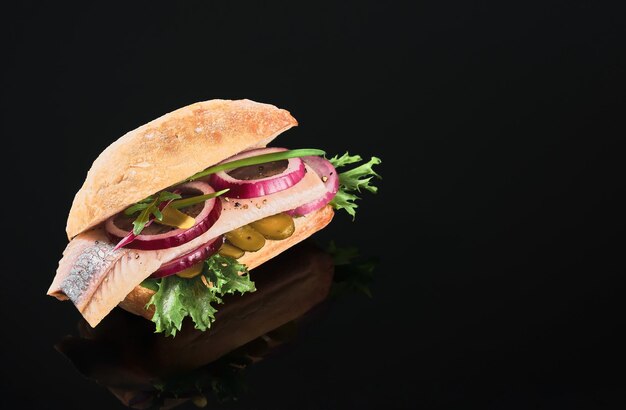 Голландский сэндвич с сельдью и солеными огурцами, маринованным огурцом и красным луком на темном зеркальном столе. Крупным планом, выборочный фокус и пространство для копирования