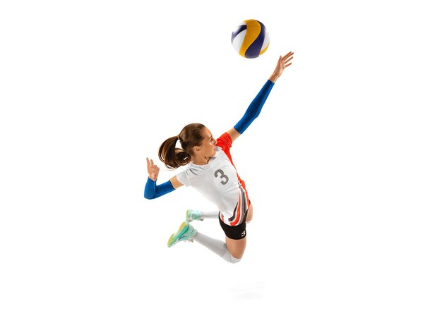 Динамический портрет молодой спортивной девушки, играющей в тренировочный волейбол на белом фоне студии