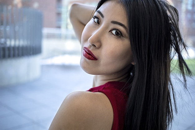 E Asian model wearing a fashionable elegant red dress and glossy red lipstick