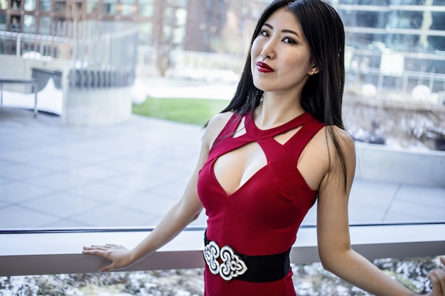 E Asian model wearing a fashionable elegant red dress and glossy red lipstick