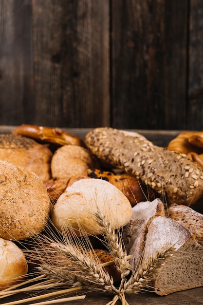 Ear of wheat in front of baked bread on wooden table