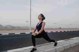 Free photo early morning time for training of young pretty woman stretching on road of tropical country. summer period, enjoying sport, relaxing.