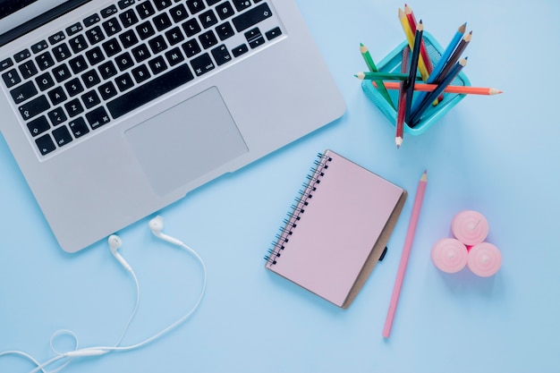 Earphones and candles near stationery and laptop