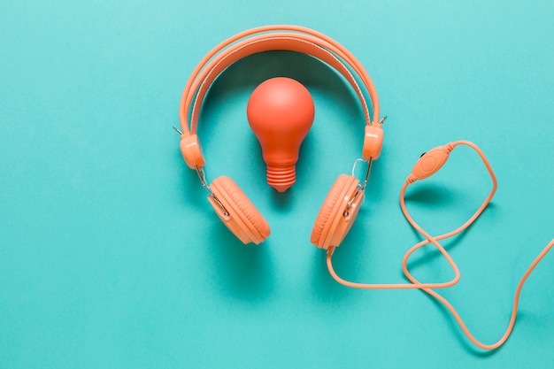 Earphones and lamp on colored surface