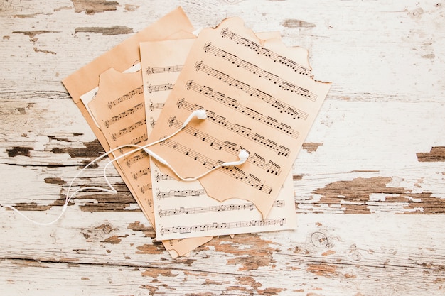 Earphones and sheet music on crumbling tabletop